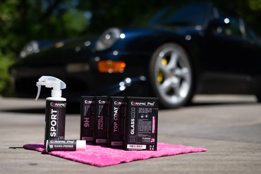 The Ceramic Pro product line on a pink towel, with a black Porsche behind it.