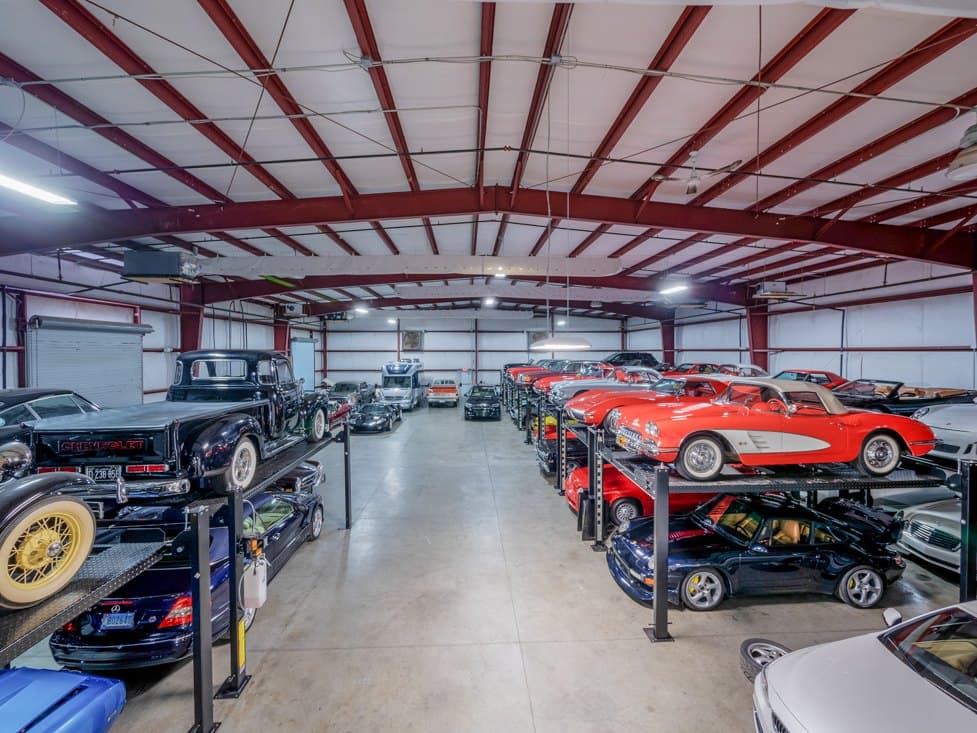 A red classic Corvette and other collector cars racked down one side of the storage floor.